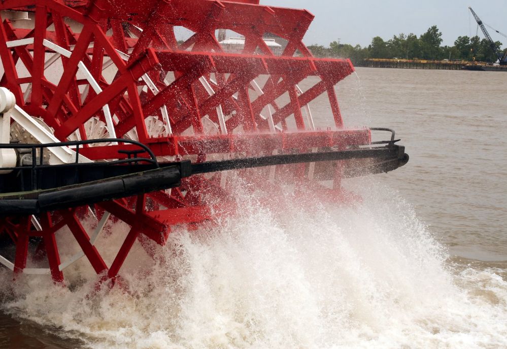 Close-up of red paddle boat wheel splashing in the water